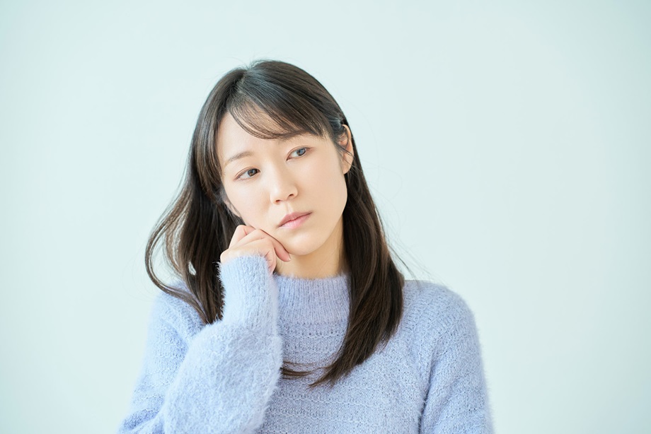 頬杖をつきながら考え事をする女性
